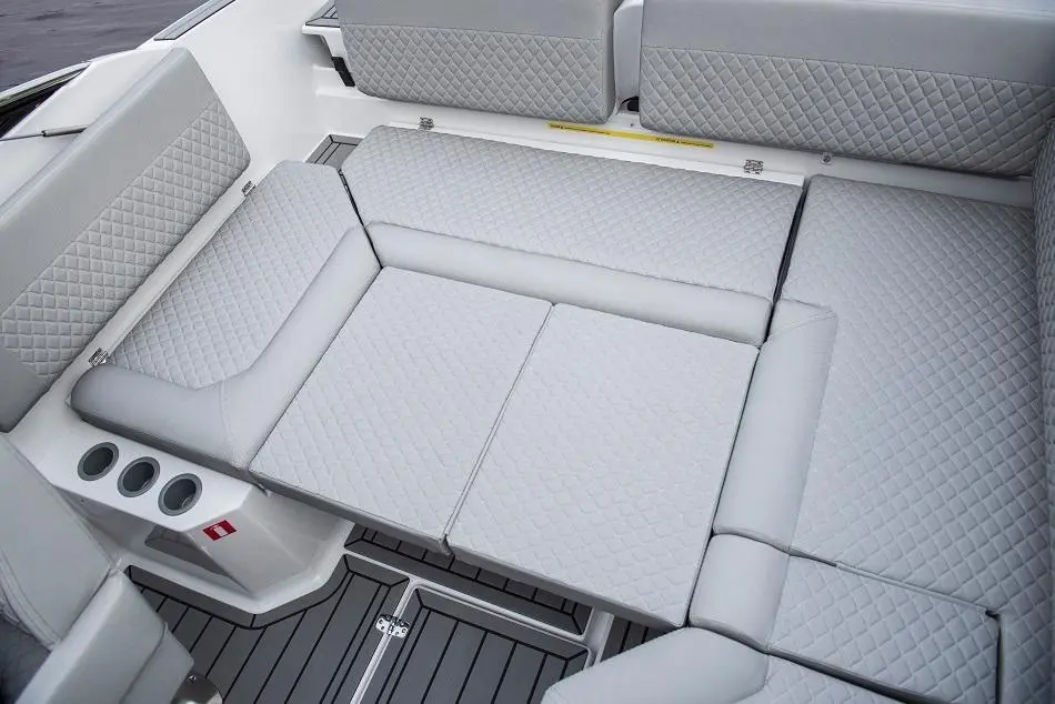 Interior of a boat featuring gray, quilted seating and cup holders on the side, with a sleek design and modern finish.
